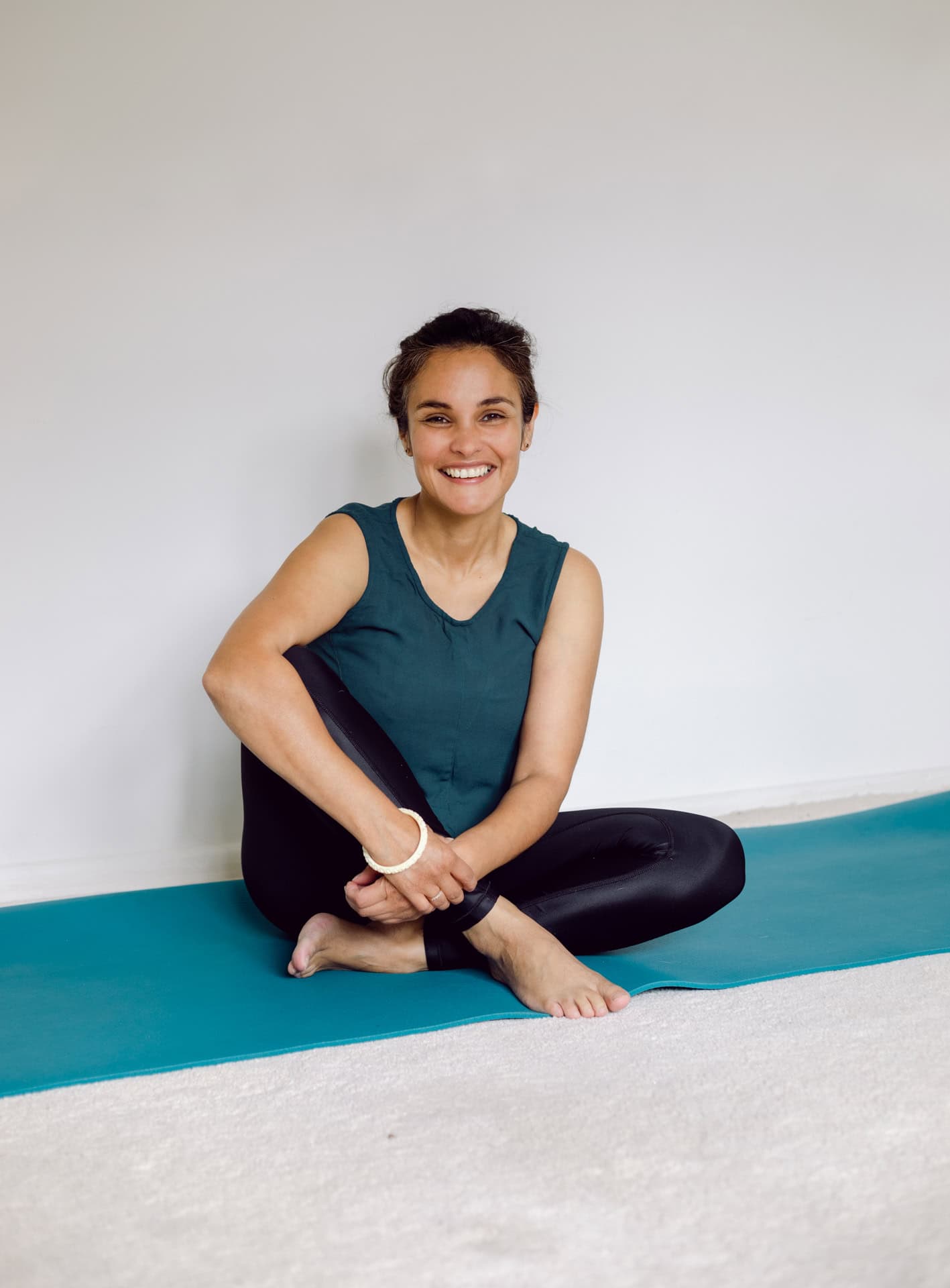 Relaxed woman doing yoga with a smile in a comfortable studio environment.