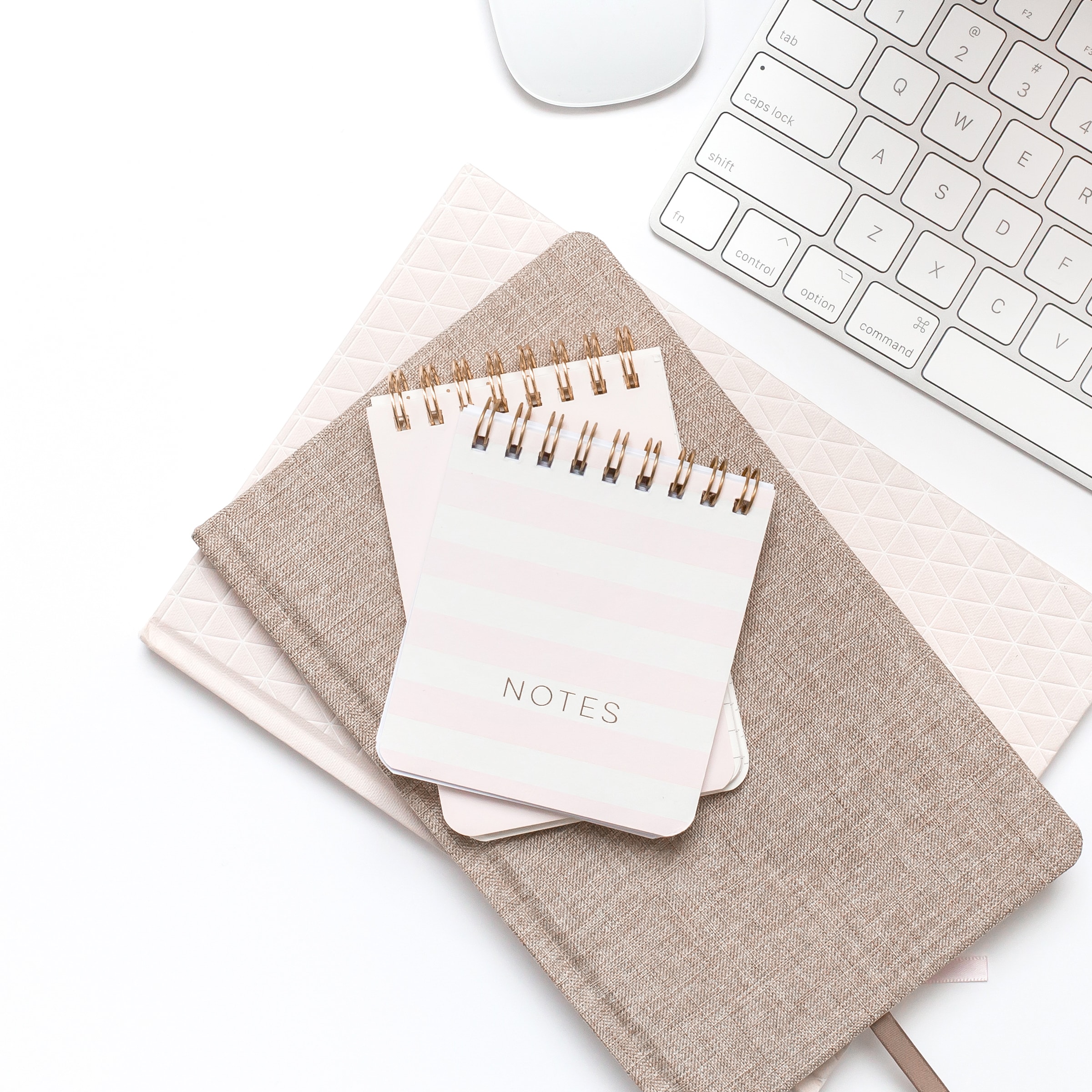 Elegant workspace with notebooks, keyboard, and mouse ideal for professional photography and branding images.