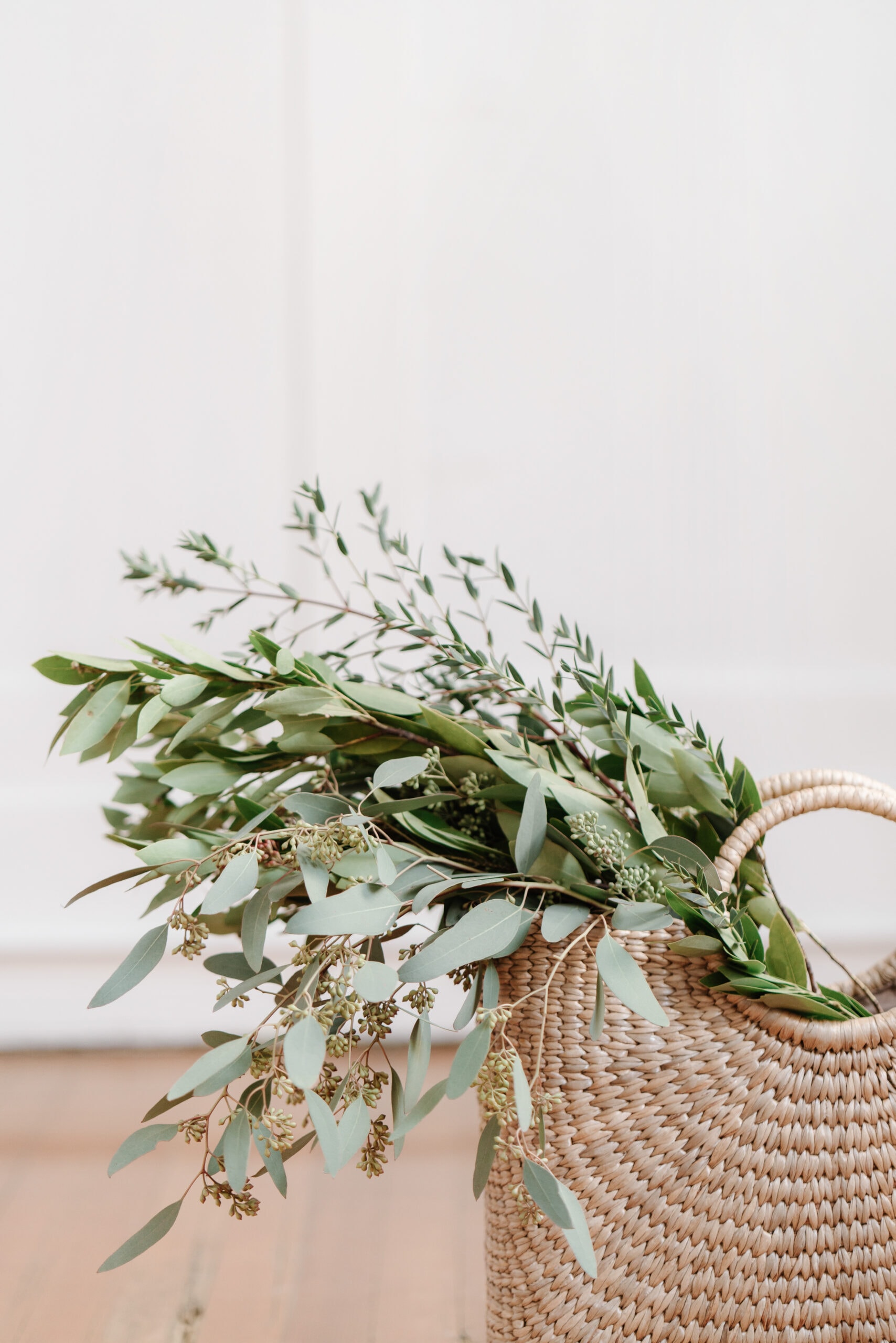 Beautiful green eucalyptus leaves in a woven basket, perfect for interior decor or floral arrangements.