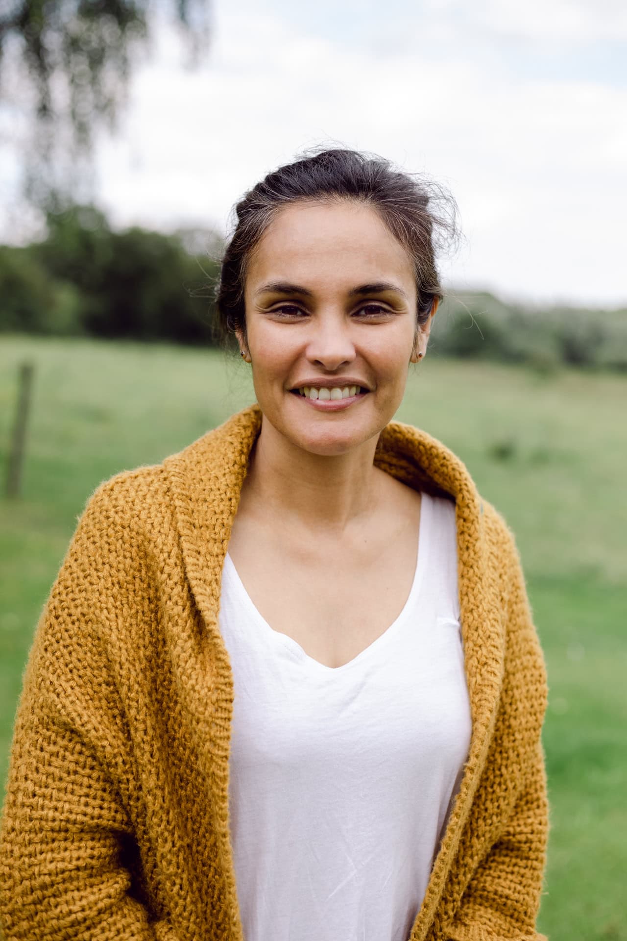 Beautiful woman outdoors, natural light, professional portrait photography, rural background, friendly smile.