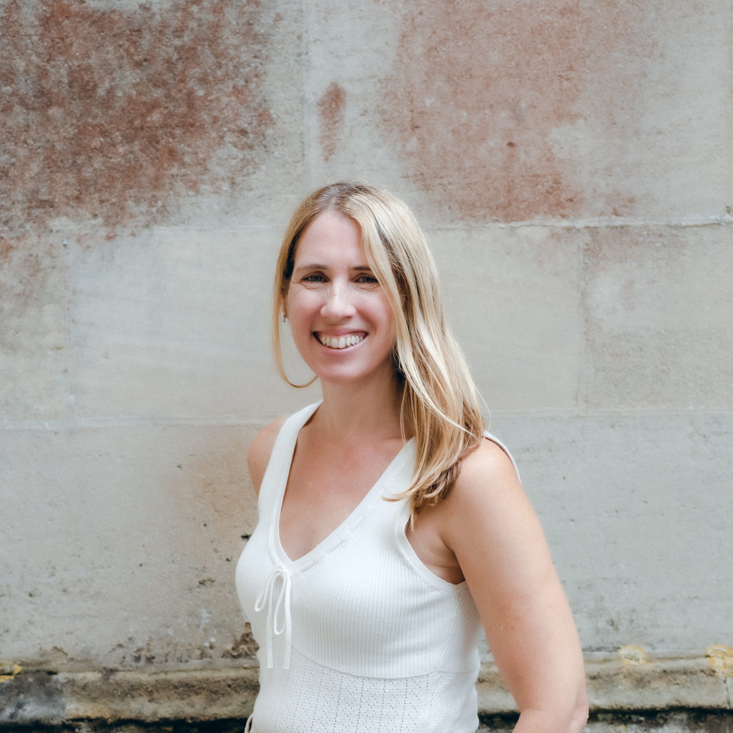 Portrait of Jo Worthington, professional photographer, smiling against a textured wall, showcasing her photography style.