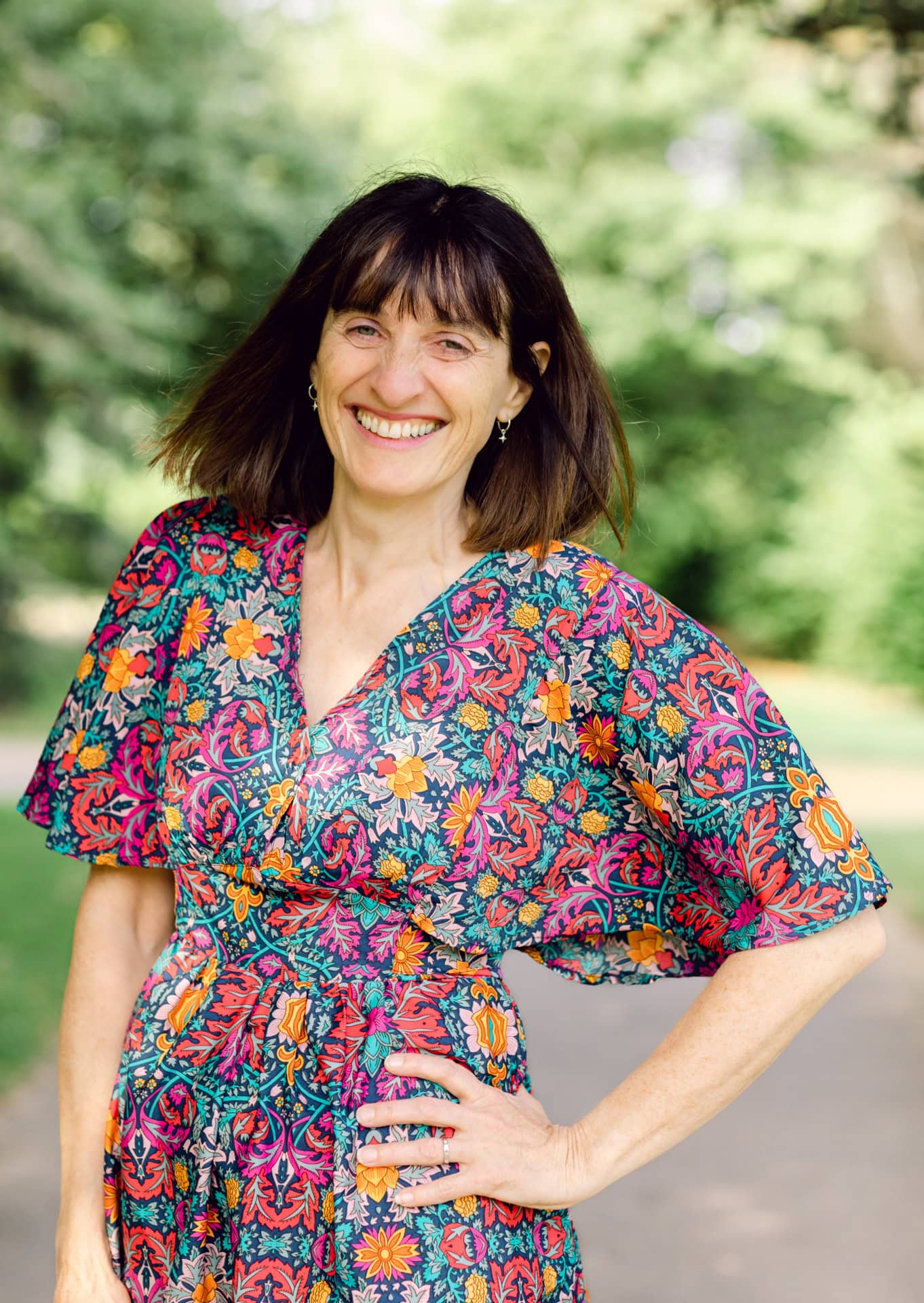 Vibrant portrait of a woman in a colourful floral dress outdoors, professional lifestyle photographer UK.